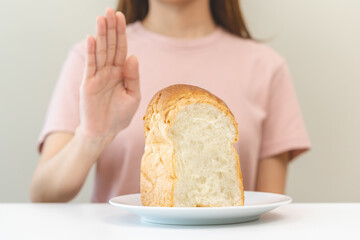 Gluten allergy, asian young woman hand push out, refusing to eat white bread loaf on plate in...