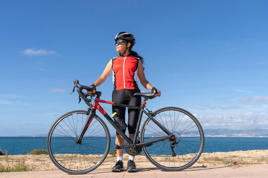 Female cyclist standing in front of her bicycle looking to the right of her. Concept of sporty, active, happy woman