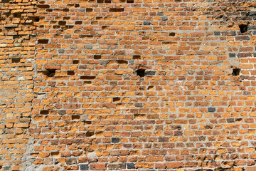 antique wall made of broken and cracked red bricks