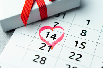 Close up calendar with 14 February date Valentines day with red heart shape marker and gift box