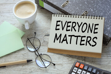 everyone matters a cup of coffee. glasses. two office folder gray notepad. text on the page