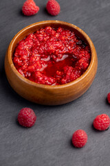 crumpled juicy red raspberries in a wooden bowl