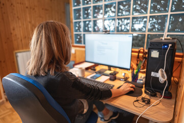 Senior woman sitting in a chair while teleworking from home with computer.