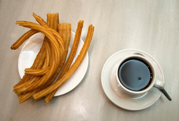 hot chocolate dipping sauce served in a cup and plate of churros, San Gines chocolateria in Madrid,...