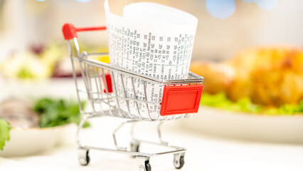 a receipt in a mini shopping cart on the table, the concept of the cost of a grocery basket