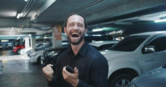 Handsome man right in parking heard about victory of his favorite team and cannot contain his emotions Person is happy screams with joy shows all his emotions Of victory always brings stormy emotions