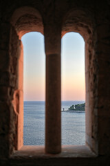 Blick durch Turmfenster aufs Meer im Sonnenuntergang