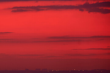 Sunset sky with red light of the setting sun. Evening clouds in the orange light of sunset rays