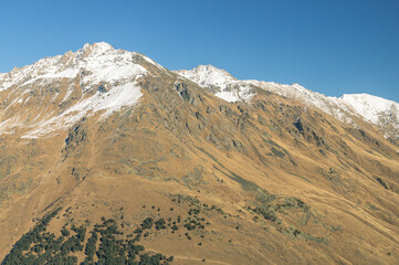 Panoramic view of snow-capped mountain peaks in clear sunny weather. Vacation at a ski resort high in the mountains. Clean air in the mountains. Outlines of mountains with icy peaks.