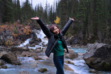 Happiness woman raise her hands up, enjoying freedom while traveling during vacation in front of falls in Yoho National Park, Canada. Life, health, energy, vision, positive, success, carefree
