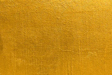 Gold wall texture background. Yellow shiny gold foil paint on wall sheet with gloss light reflection, vibrant golden paper luxury wallpaper