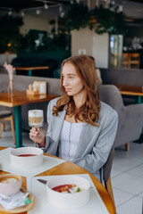 Young beautiful stylish woman drinking coffee while sitting in restaurant. Coffee break time