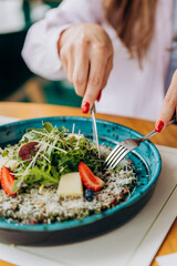 Close up of woman eating beef carpaccio with pesto sauce and parmigiano cheese. Restaurant menu