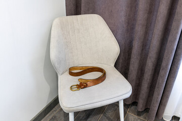 Corporal punishment. Domestic discipline, domestic violence, and abuse at home. Brown leather belt on a chair. Adult role play, spanking implements, bdsm toys