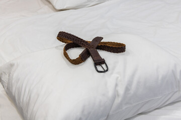 Corporal punishment. Domestic discipline, domestic violence, and abuse at home. Brown leather belt on a pillow ready for spanking. Adult role play, spanking implements, bdsm toys