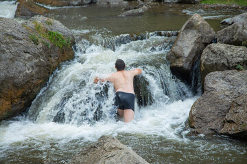 Back view of man in small waterfall.