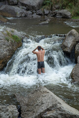 Fototapeta na wymiar Back view of man in small waterfall.
