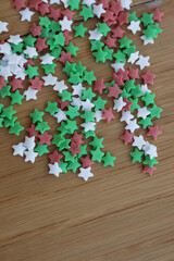 Christmas green, red and white star shaped sprinkles on wooden table. Festive background