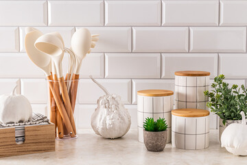 Modern kitchen background with elements of natural decor, white decorative pumpkins. Stylish jars...