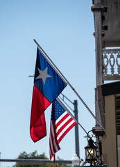Flags of Texas state and USA flying side by side on main street