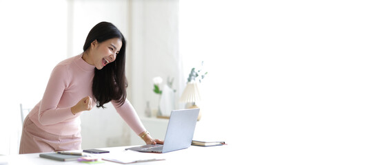 Woman looks at laptop and looks happy and successful.
