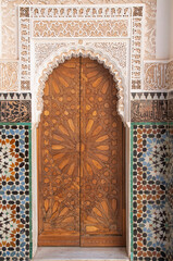 Wall and wooden door of main courtyard in madrasa Ben Youssef Madrasa in Marrakesh, Morocco
