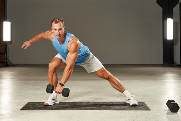 Caucasian athlete trains his legs with a dumbbell in his hand. fitness. aerobics. exercises on the mat. physical health