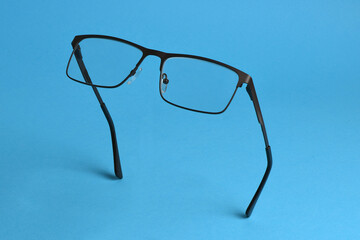 Reading glasses isolated on blue background. Glasses hang in air