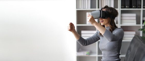A woman sitting on a sofa in the living room wearing VR 3D glasses looks excited about a movie.