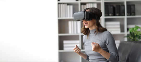 A woman sitting on a sofa in the living room wearing VR 3D glasses looks excited about a movie.