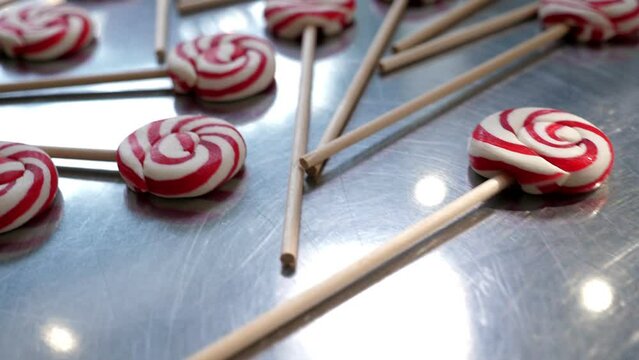 Close-up of many different red and white lollipops in a candy store on a metal table. Production of handmade caramel candies.