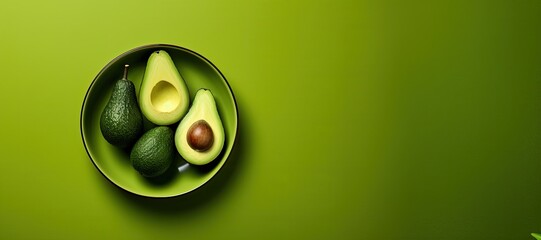 Monochrome image of ripe avocados in a bowl on a green background.