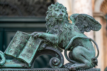 Winged lion of Saint Mark holding bible in front of Venetian Campanile