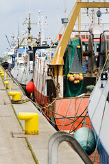 A line of trawlers berthed at a harbour wharf.