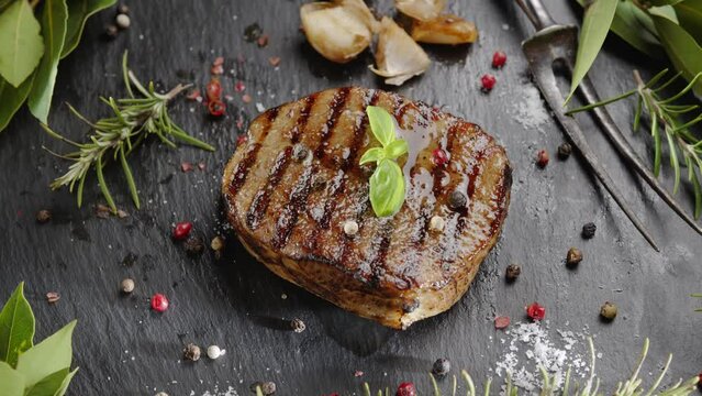 Cooked grilled ribeye steak on a gray serving stone with fried garlic and steam emanating from it. Great food background for your projects.