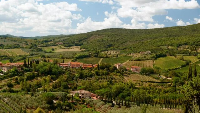 Establishing shot of green rolling hills, cypress tress and rustic houses of San Gimignano, Tuscany, Italy