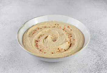 Classic hummus in a white plate on a gray background. Arabic, Turkish cuisine