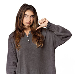 Young Caucasian woman in studio setting showing thumb down, disappointment concept.