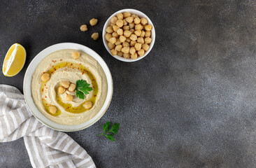 Classic chickpea hummus with, olive oil, parsley and lemon on a dark background. Top view. Copy space. Arabic, Turkish cuisine.
