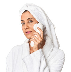 Middle-aged woman using electric facial cleaner in studio