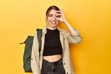 Young traveler woman with her backpack excited keeping ok gesture on eye.