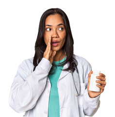 Young Filipina doctor holding a pill bottle is saying a secret hot braking news and looking aside