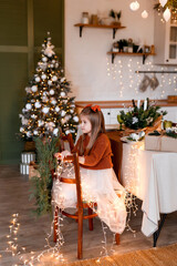 Merry Christmas and Happy Holidays. Cheerful cute child girl having fun in Christmas interior.