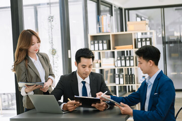 Group of young Asian business people discussing business plan at modern startup in creative business discussing work modern office .