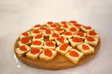 Canapes with red caviar on a wooden stand. Cold snacks from the buffet table.