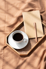 Coffee cup and notebook on bed. Cozy morning still life.