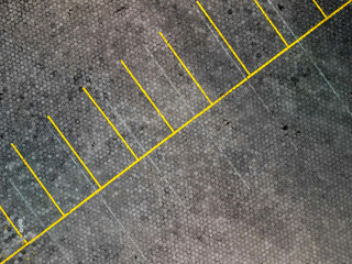 Aerial view of outdoor vehicle parking area in urban areas with paving blocks and yellow lines for dividing signs between parked vehicles. Cars parking lot during the day with 90 degree angle.