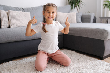 Active and energetic little girl have fun and home. Living room. Kid sitting on the carpet.
