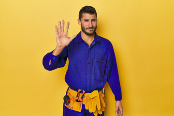 Young Hispanic man in a blue jumpsuit Young Hispanic man in a blue jumpsuitsmiling cheerful showing...