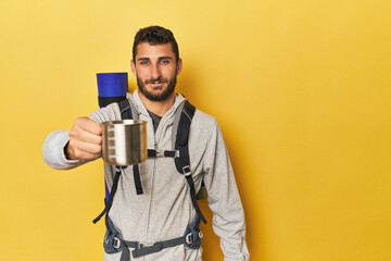 Young Hispanic man with camping mug and pack